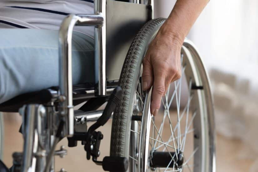 Person Laying His Hand On A Wheelchairs Tire Holder