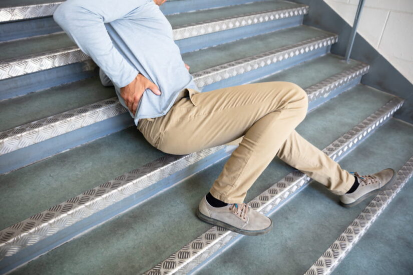 Man Holding His Lower Back In Pain Laying On Stairs