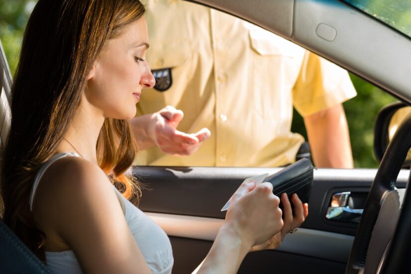 Driver Handing Over Her Documents To A Police Officer