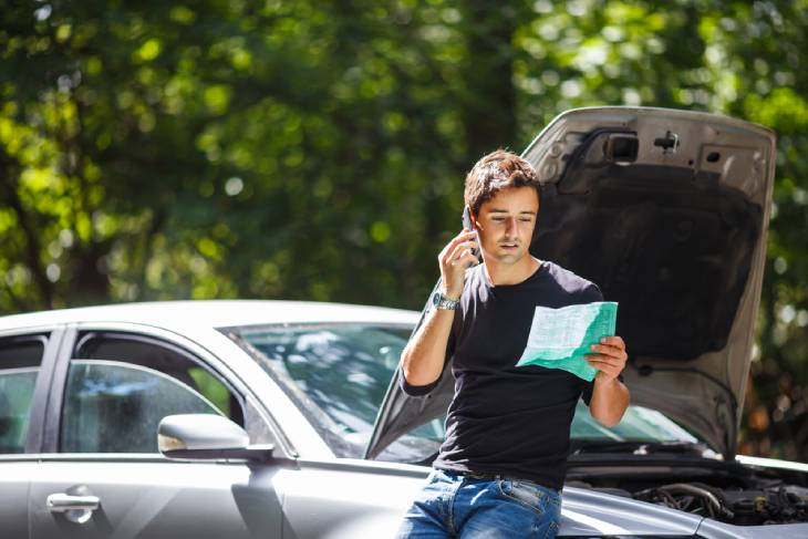 Photo of a man with the phone next to the car