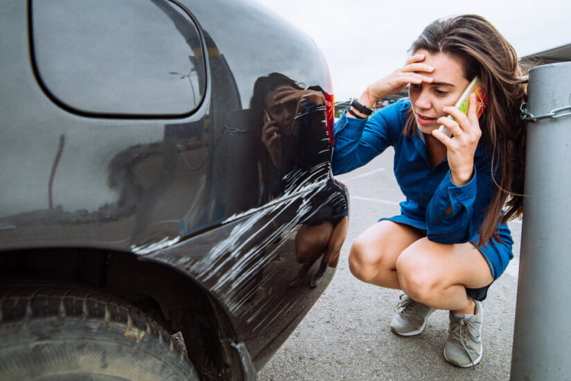 Woman Talking On Phone And Looking On A Car Scratch