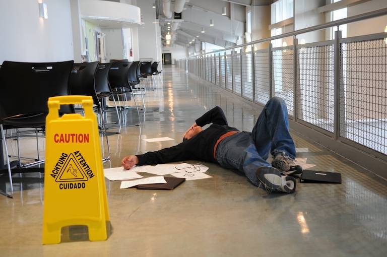 Person Laying On The Floor By The Wet Floor Sign