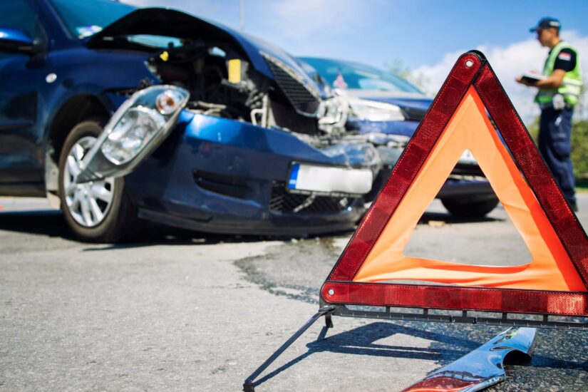 Warning triangle for traffic and damaged cars in the middle of an intersection.