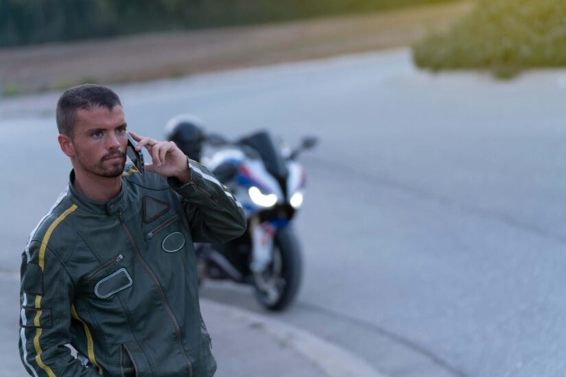 Young man with broken motorcycle on the road talking on the phone